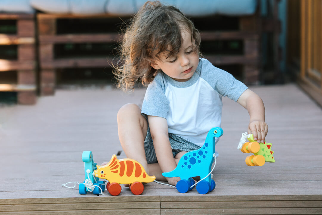 Stegozaur - dziecko bawiące się zabawkami drewnianymi od Trefl